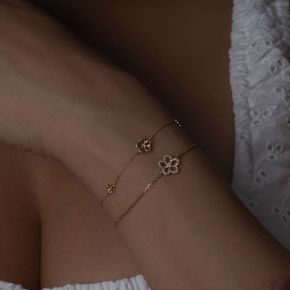 Gold and diamond flower bracelet stacked on models wrist