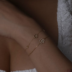 Gold and diamond flower bracelet stacked on models wrist