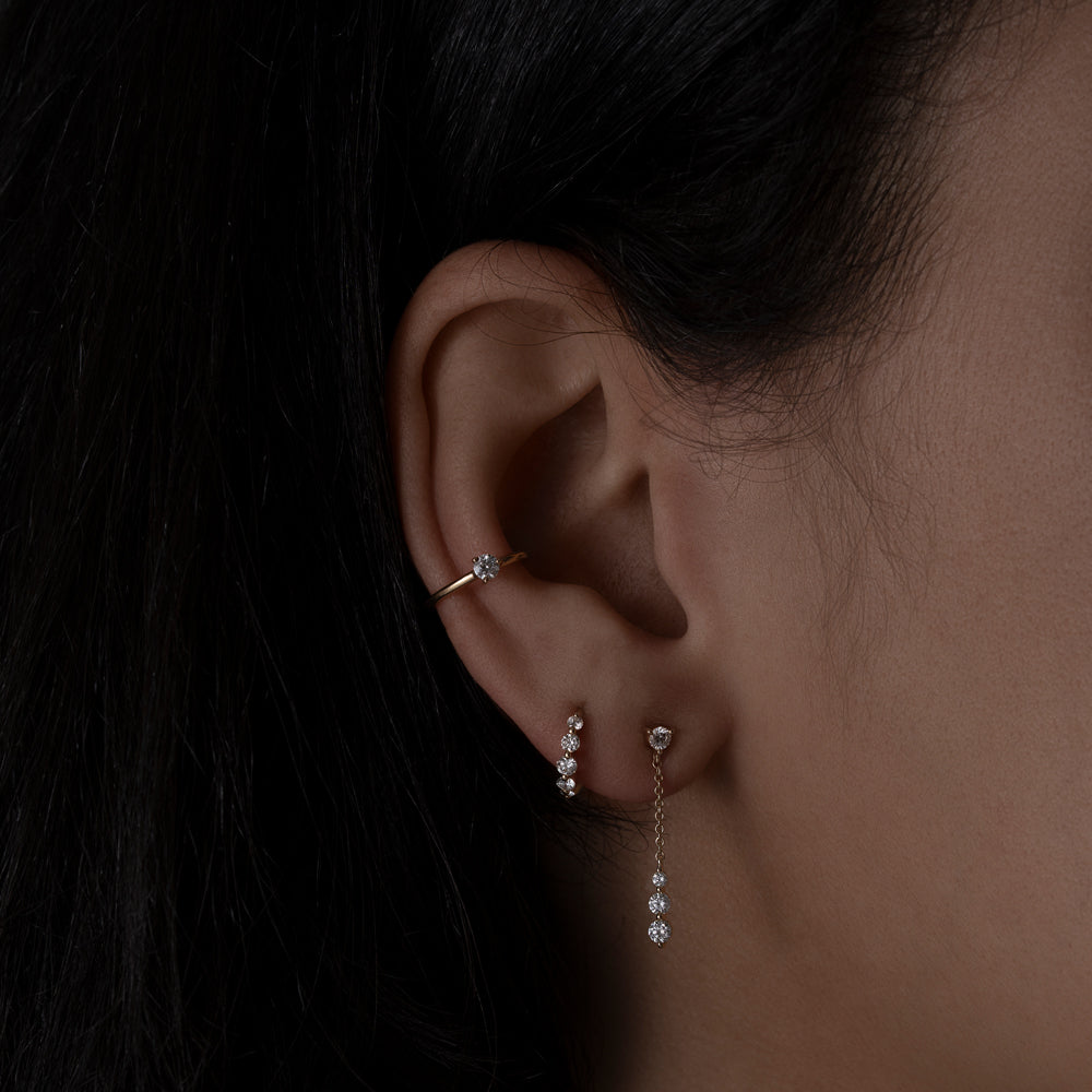 Graduated diamond earrings stacked on an ear